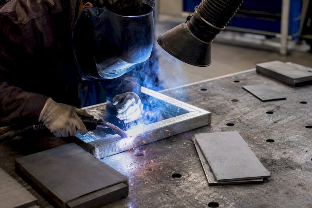 Soudeur en plein travail sur de l’acier galvanisé dans un atelier.