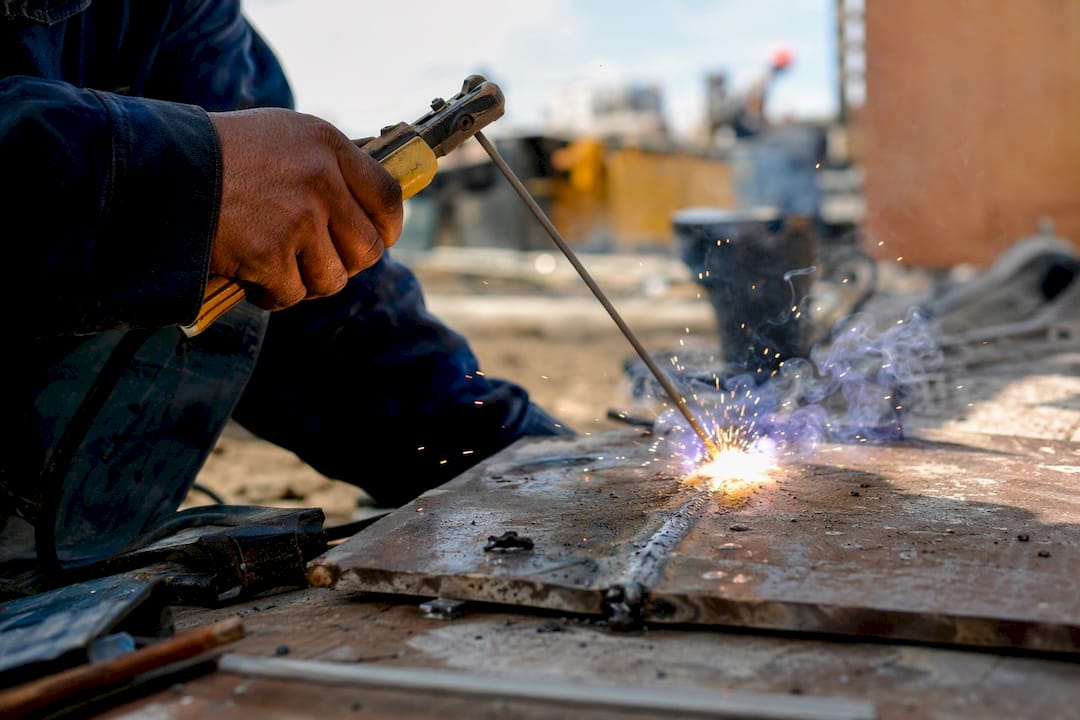 Hands performing stick welding on galvanized steel