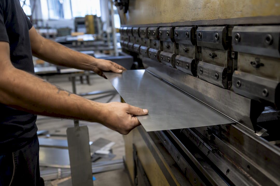 Hands bending galvanized steel sheet for plenum