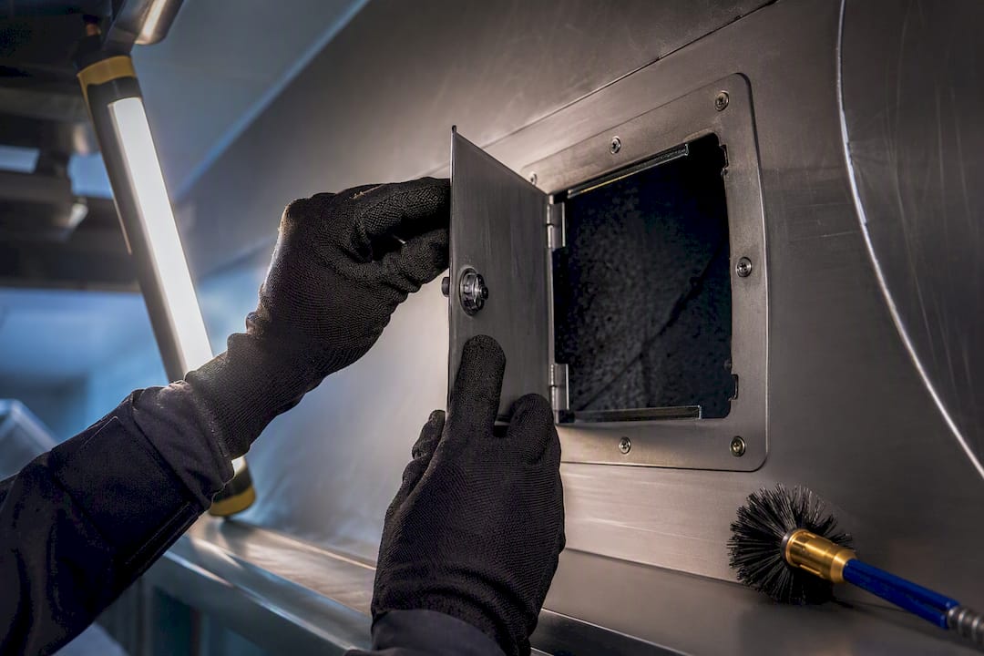 Technician opening kitchen duct access panel