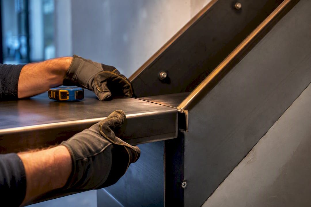 Fabricator aligning a custom metal stair tread
