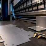 Tôle plate et pièce pliée devant la presse plieuse