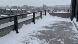 Uneven snow drift beside rooftop terrace railing