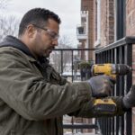 Poseur en train de fixer un garde-corps sur une paroi en brique