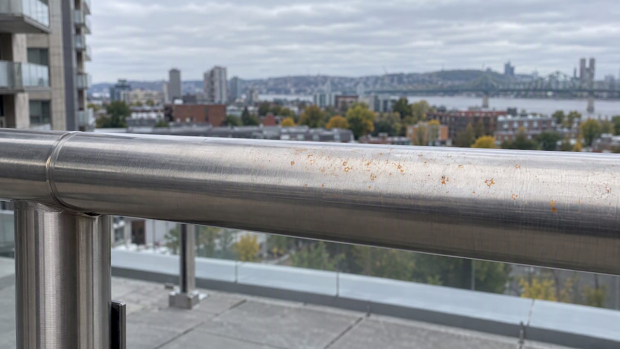 Petites taches oranges sur un garde-corps en inox